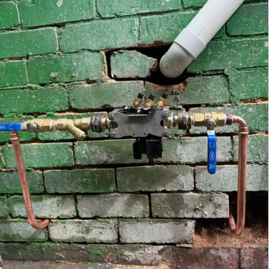 Copper pipe repair with new valves on a green painted brick wall