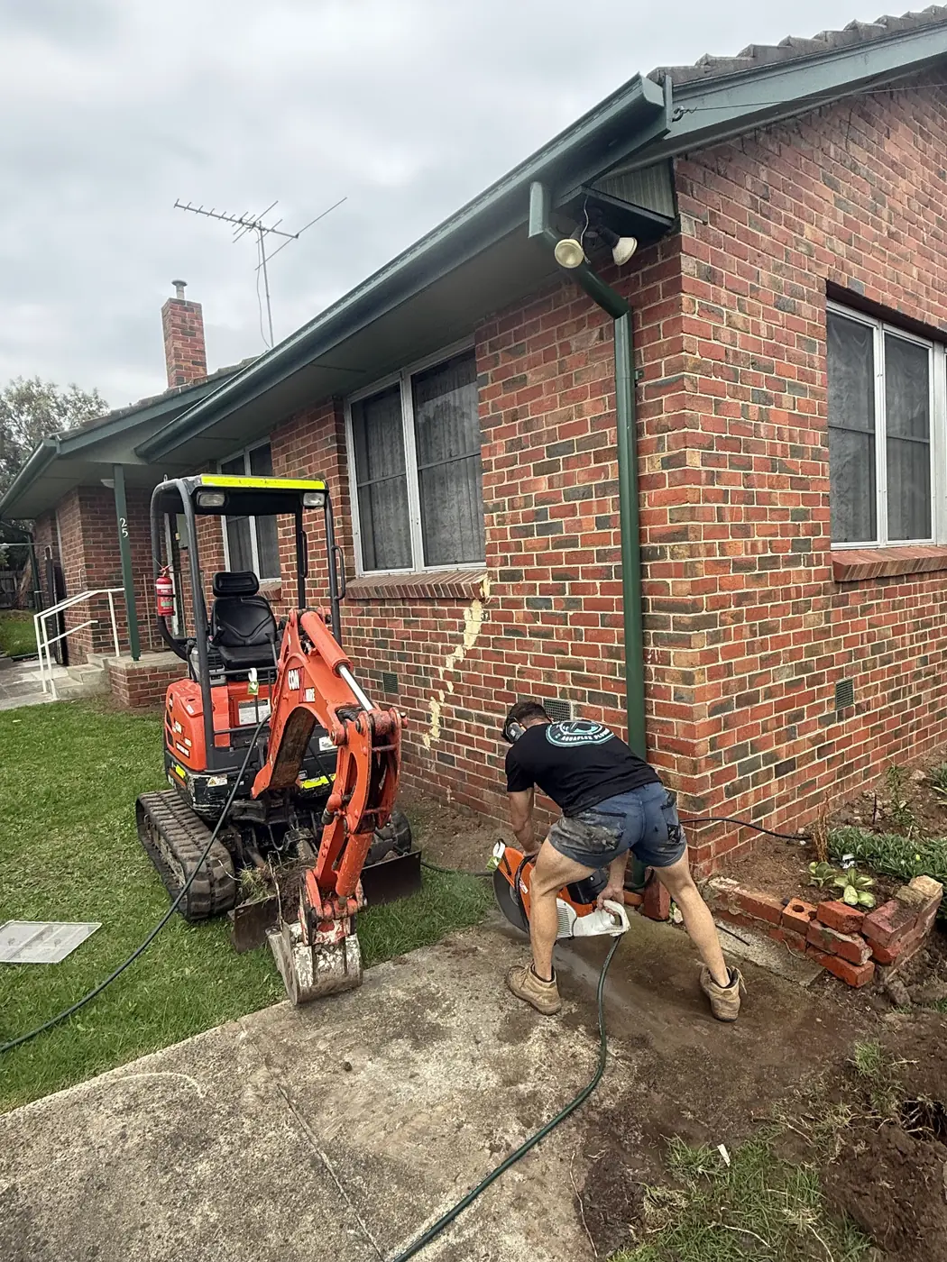 Mini excavator working beside a brick home