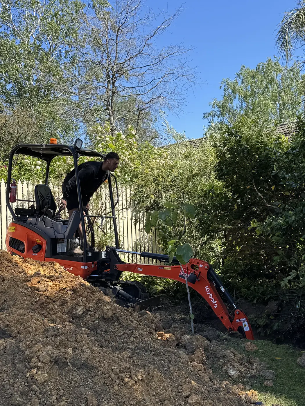 Aquaflex mini excavator digging a sewer trench in a backyard