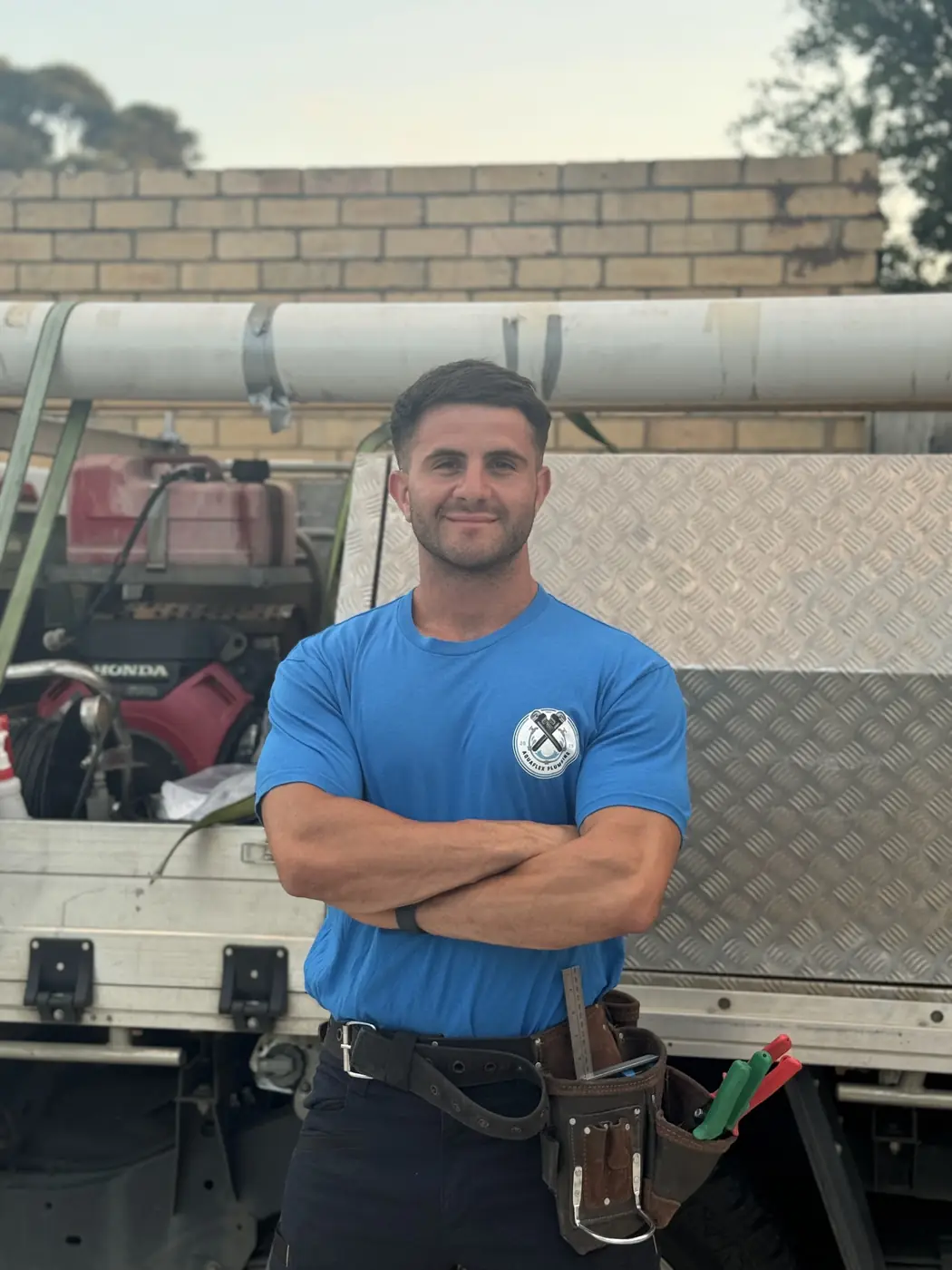 Yianni from Aquaflex Plumbing standing beside the ute, arms crossed
